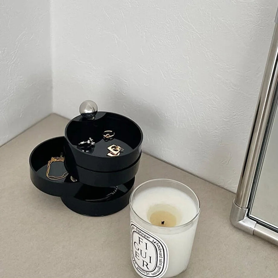 Close-up of the Matte Black rotating jewelry box, with various rings and earrings visible in its tiers. - RoomDen