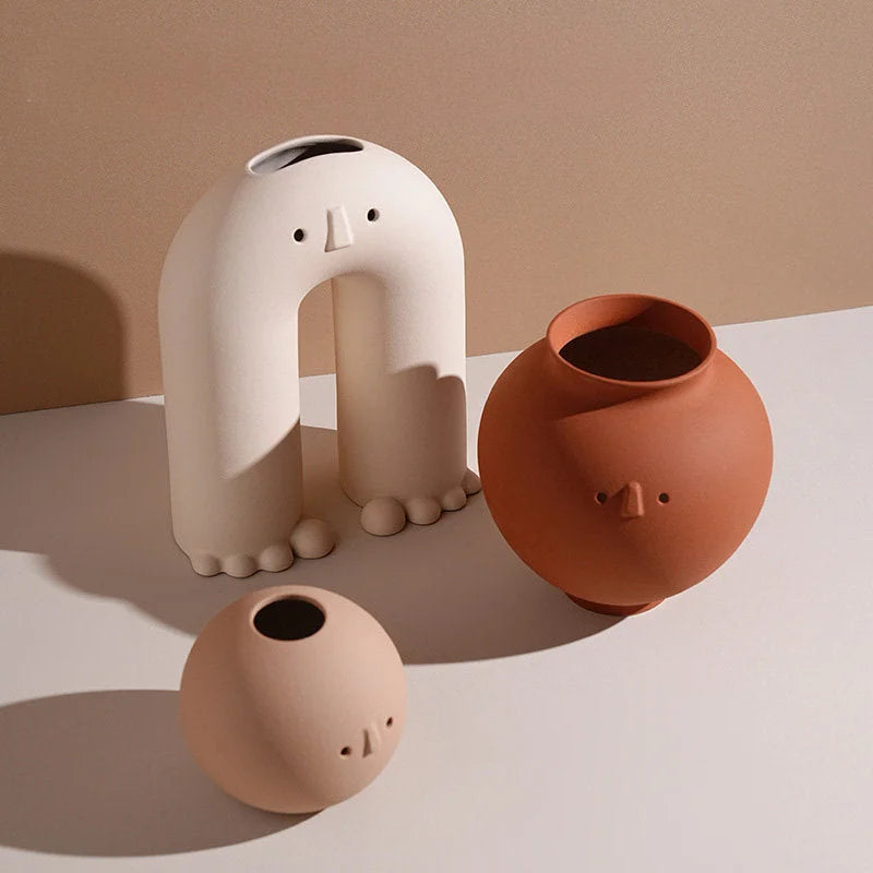 The trio of Arch, Pot, and Ball Frosted Minimalist Face Vases on a light surface, showcasing their different shapes and sizes. - RoomDen