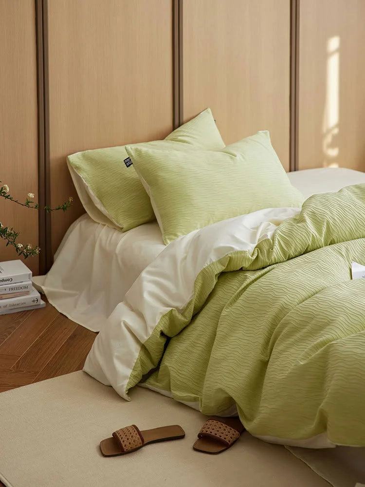 Close-up of the Matcha Green & Cream White Wavy Textured pillow shams on a bed. - RoomDen