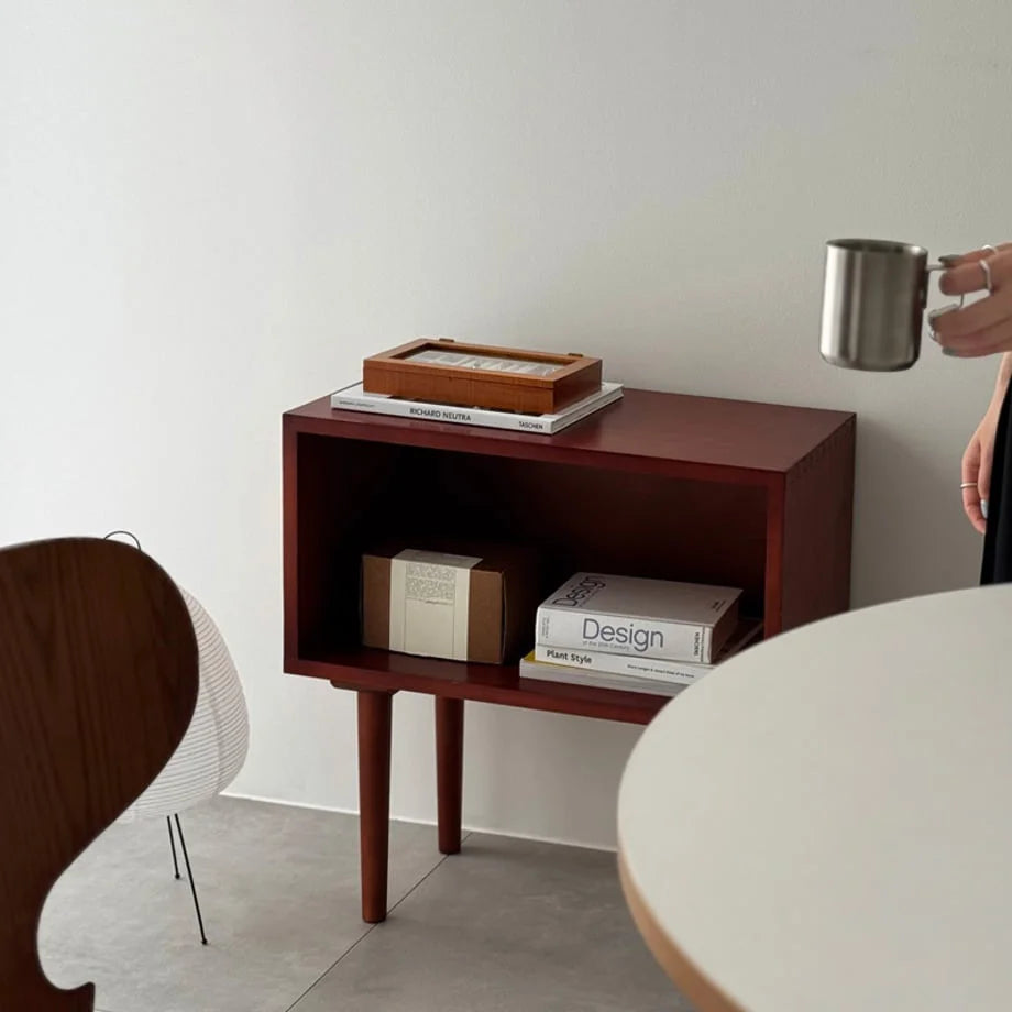 A lifestyle scene showing the wood jewelry box resting on a dark wood side table with books.