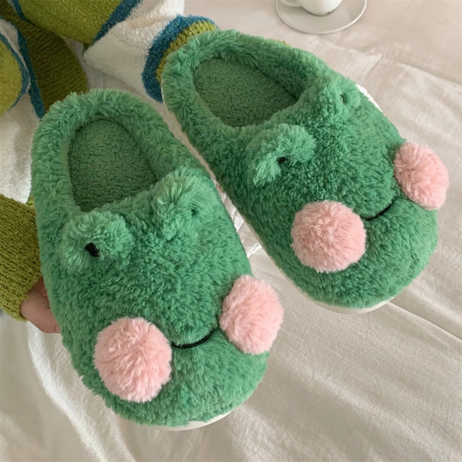 Top down view of cute kawaii frog slippers on bed sheets - RoomDen