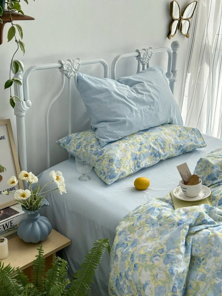 Close-up of the reversible design, showing a solid light blue pillowcase against the floral patterned ones. - RoomDen