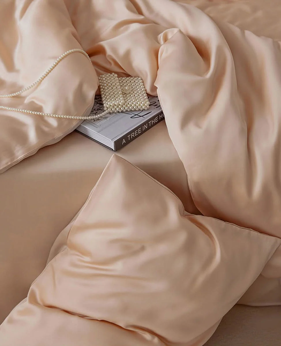 Detail shot of the soft folds of the Blush Pearl Tencel duvet cover with a pearl accessory. - RoomDen