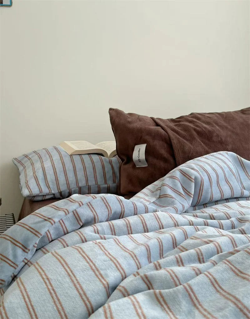 Cozy Blue Striped Bedding Set with Brown Accent Pillow on Bed