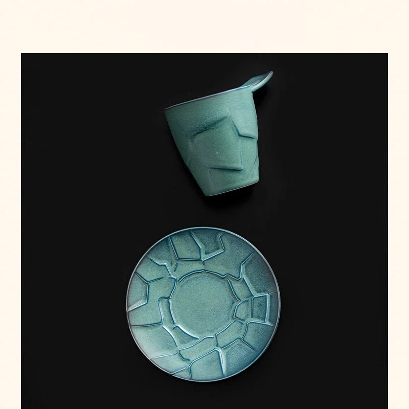 Top-down view of the Sage Green Textured Geometric Ceramic Coffee Cup and its cracked-pattern saucer on a black surface - RoomDen