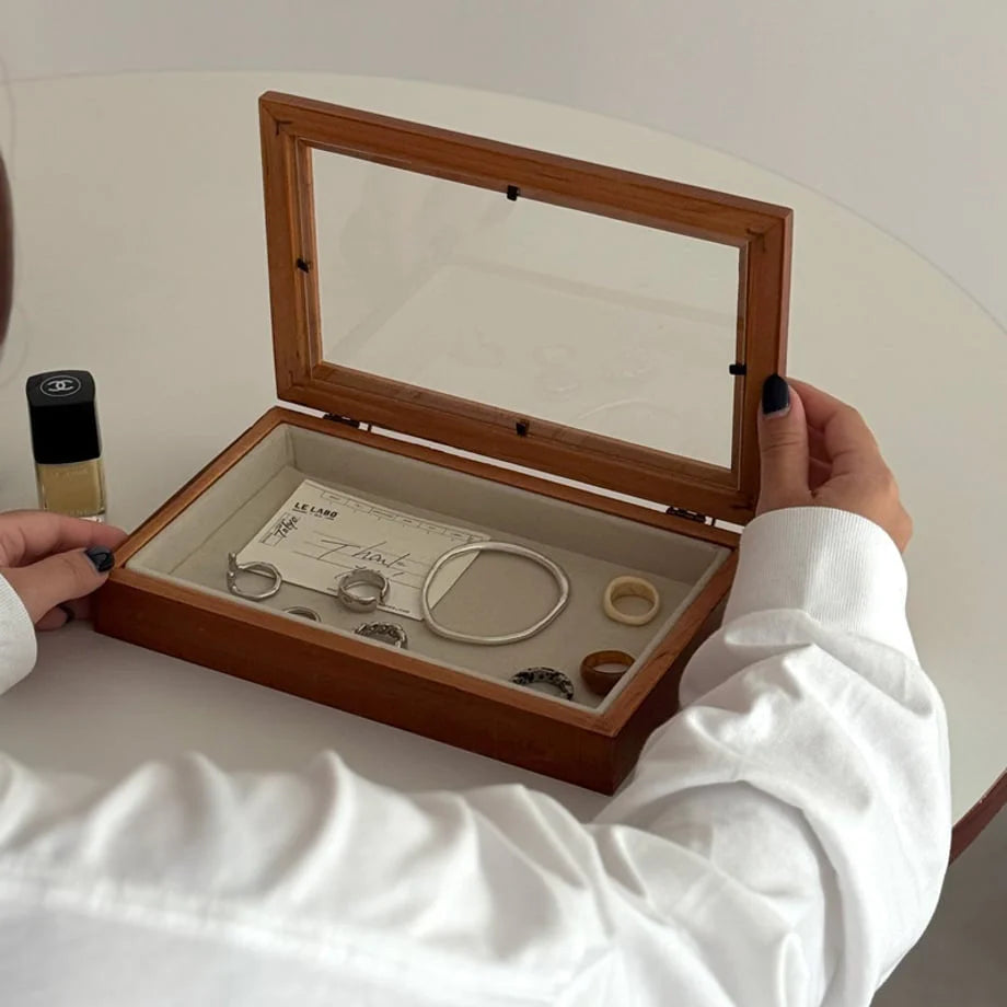 Close-up of a woman's hands opening a wood and glass jewelry organizer filled with accessories. - RoomDen