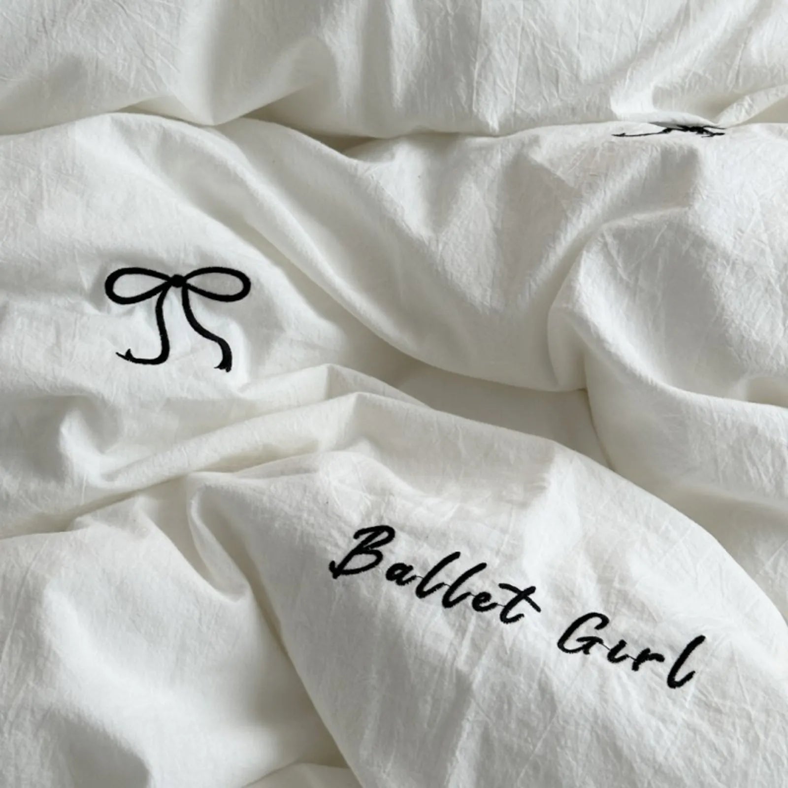 A detailed close-up of the textured white duvet cover, highlighting the black "Ballet Girl" script and bow embroidery.