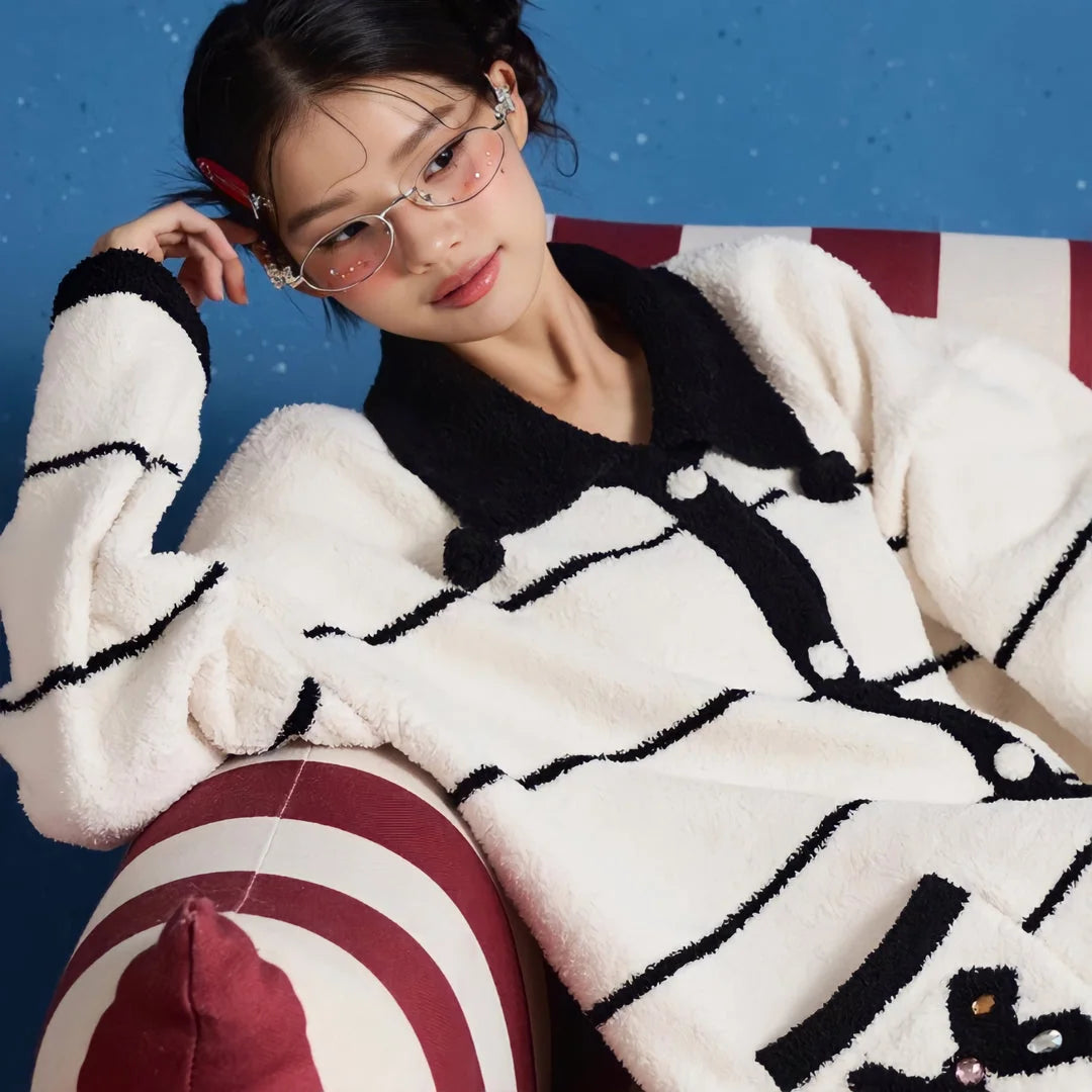 Model lounging on a striped armchair in the cozy white and black fleece pajama set - RoomDen.