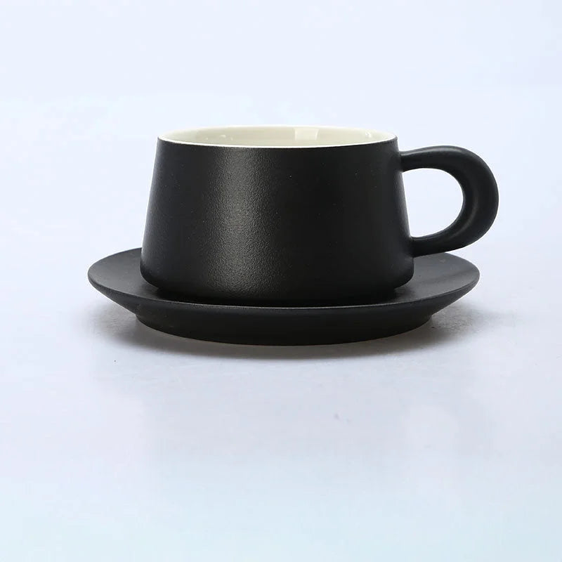 A Matte Black ceramic coffee cup with a chunky handle and matching saucer on a white background. - RoomDen