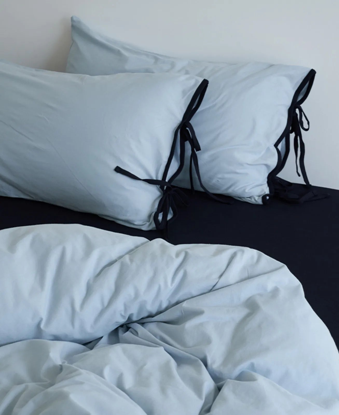 The Sky Blue & Black duvet cover and pillows arranged artfully on a dark sheet. - RoomDen