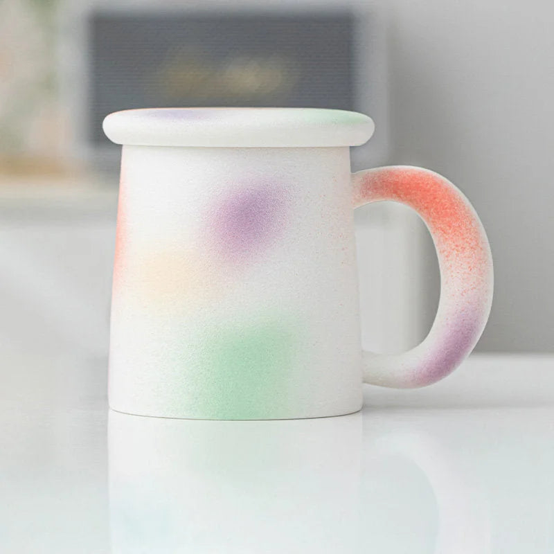 Angled view of the Pastel Sprinkle Frosted Ceramic Mug with lid - RoomDen.