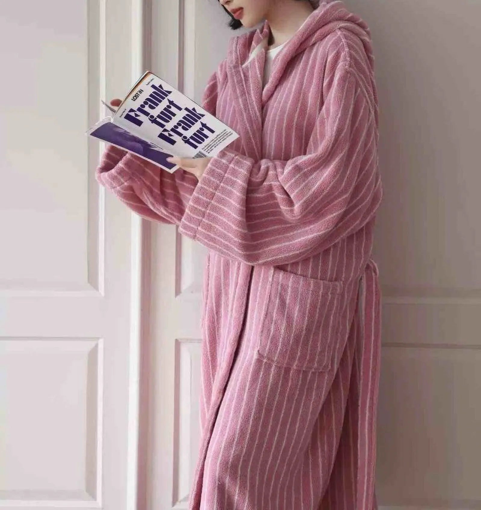Detailed view of the pink and white striped pattern on a hooded robe, woman reading - RoomDen