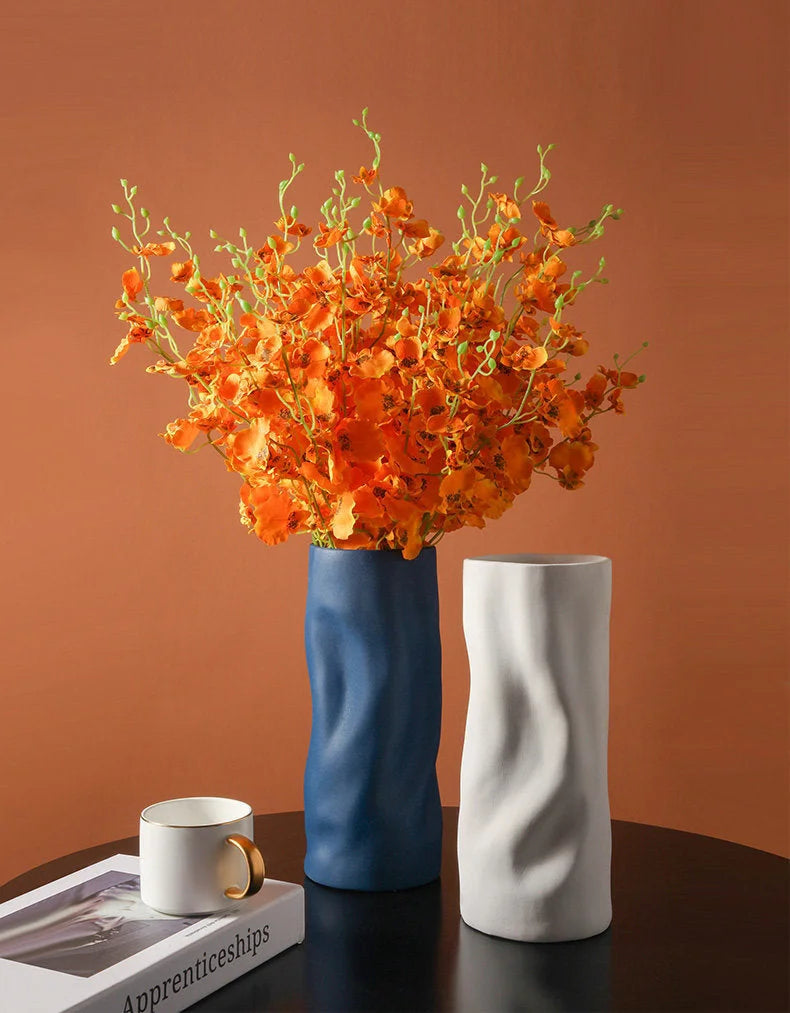 The Midnight Blue and Cream white Ruched Ceramic Vases styled together on a dark wood table, one holding orange flowers - RoomDen.