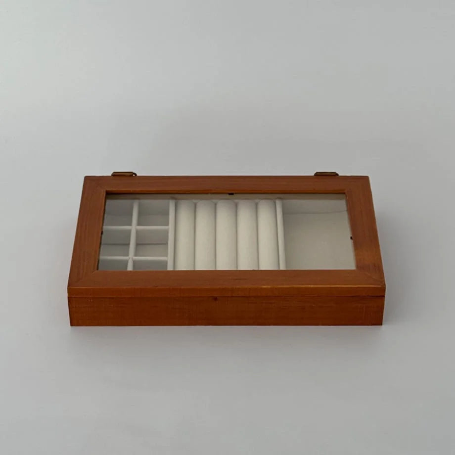 An angled top view of the closed wood jewelry organizer, showing the interior compartments through the glass lid.