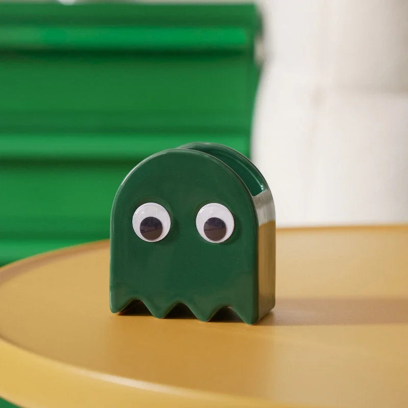 The green Retro Ghost Ceramic Pen Holder on a yellow table with a green background - RoomDen.