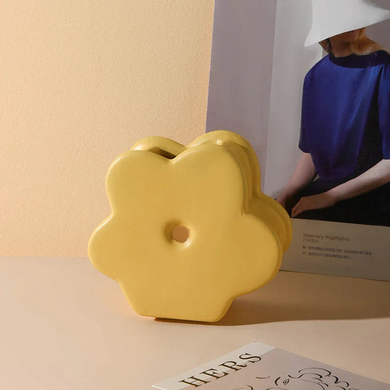 The Butter Yellow Daisy Bloom Ceramic Vase shown against a neutral background with a magazine. - RoomDen