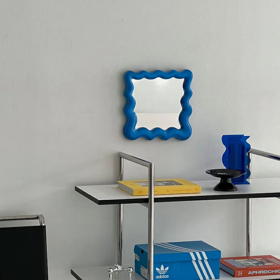Angled view of the blue squiggle mirror on a wall, showing its playful design in a minimalist room - RoomDen