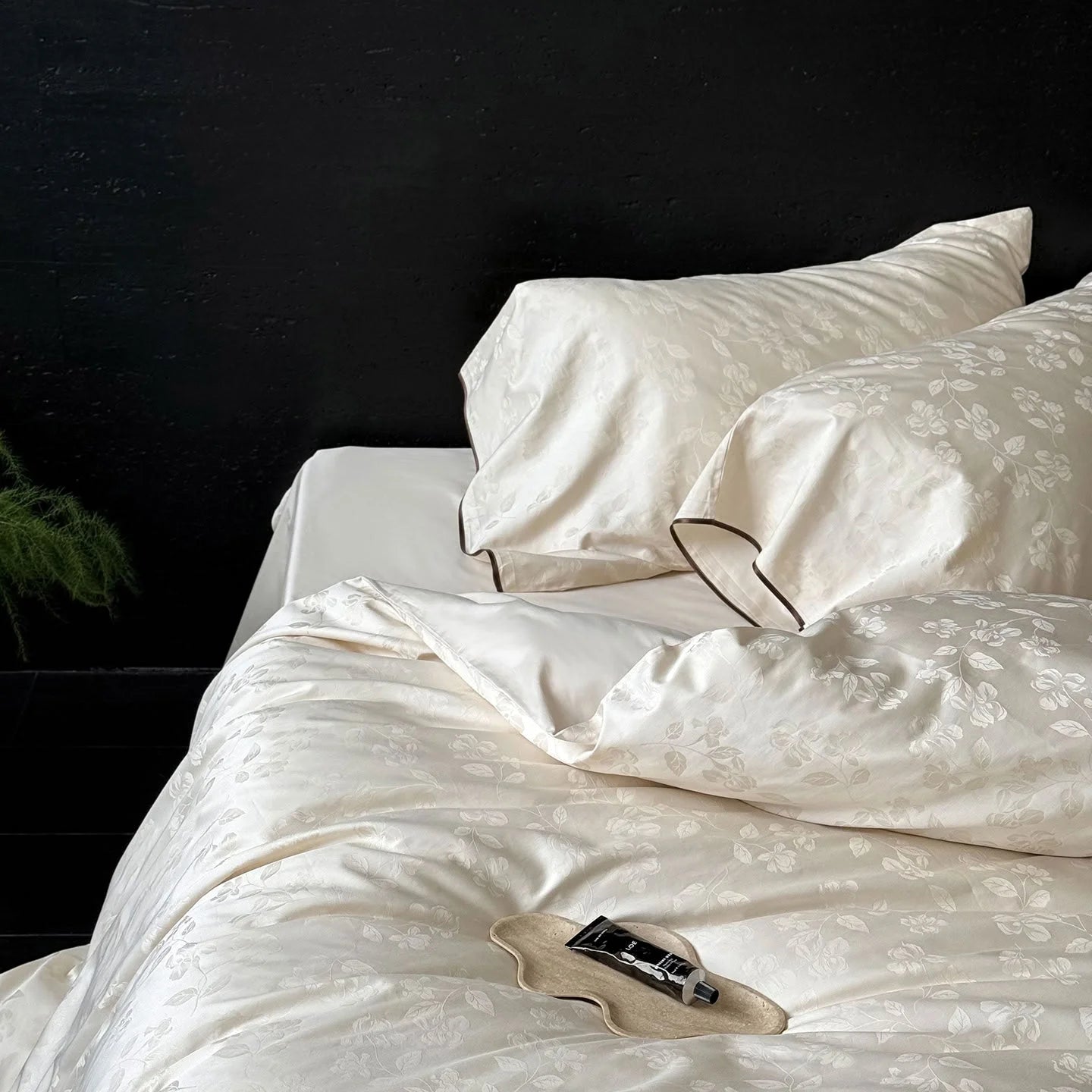 Angled view of the Pearl White Tencel bedding, focusing on the pillowcases with their dark contrast piping detail.