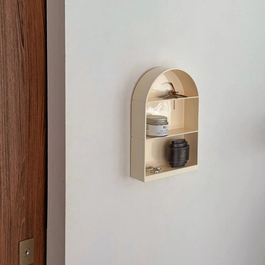 Angled view of the minimalist arched wall shelf mounted on a white wall near a door - RoomDen.