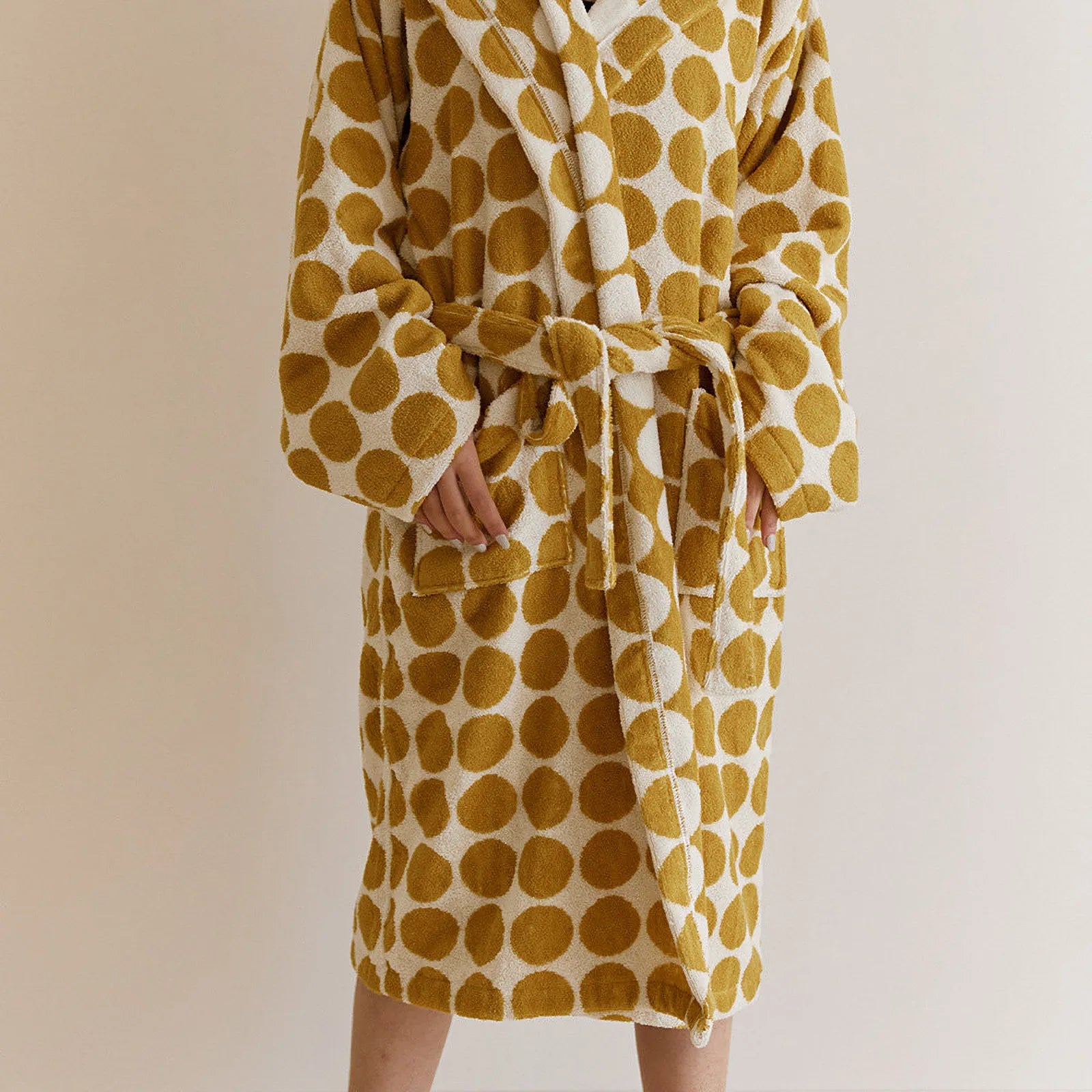 Front view of a person wearing a hooded yellow and white polka dot cotton robe with hands in pockets - RoomDen