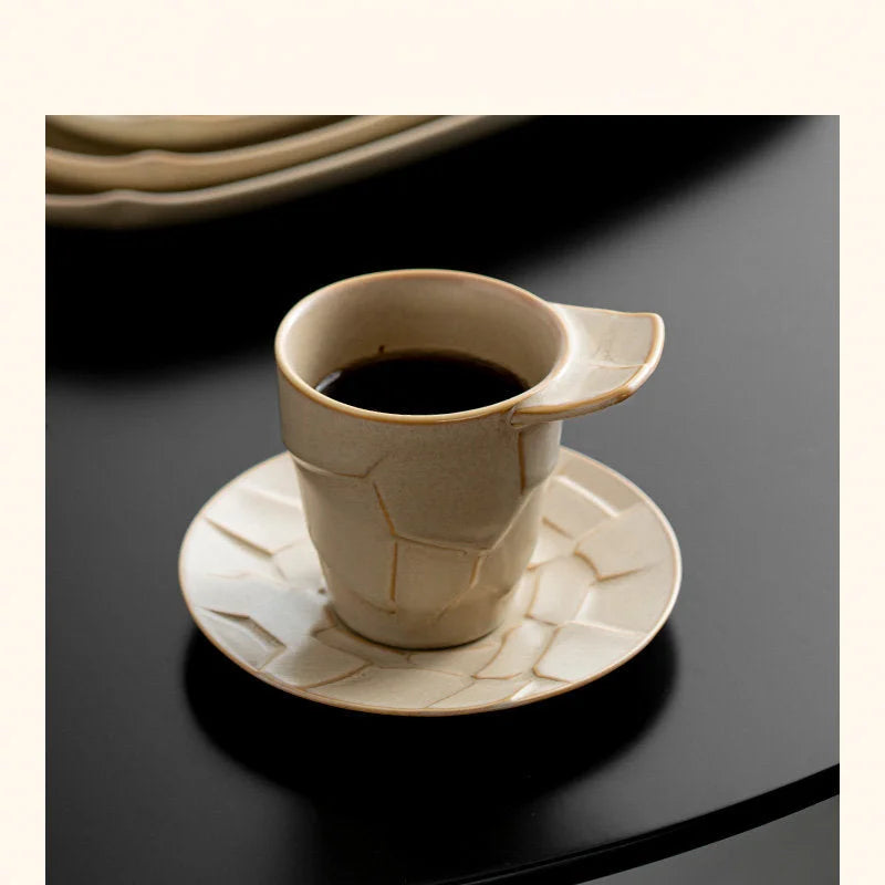 A Sandstone Beige Textured Geometric Ceramic Coffee Cup and Saucer on a dark table, ready for coffee - RoomDen