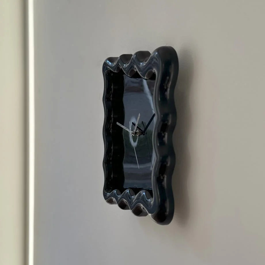 Angled close-up of the glossy black Wavy Squiggle Clock, showing its three-dimensional ruffled frame. - RoomDen