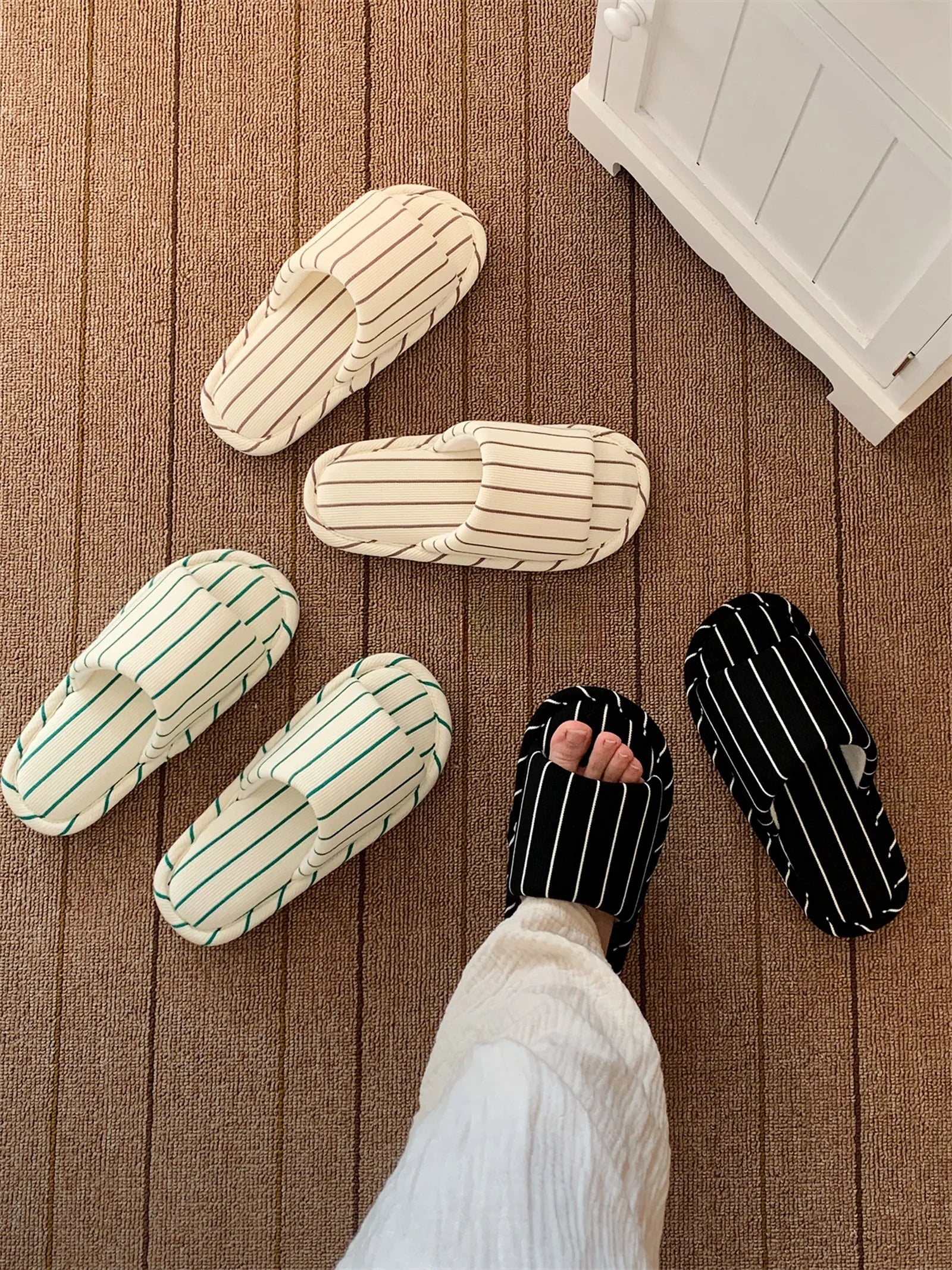 RoomDen Soft Ribbed Striped Cotton House Slippers arranged on a brown textured rug, showing Beige, Black, and Green color variations.
