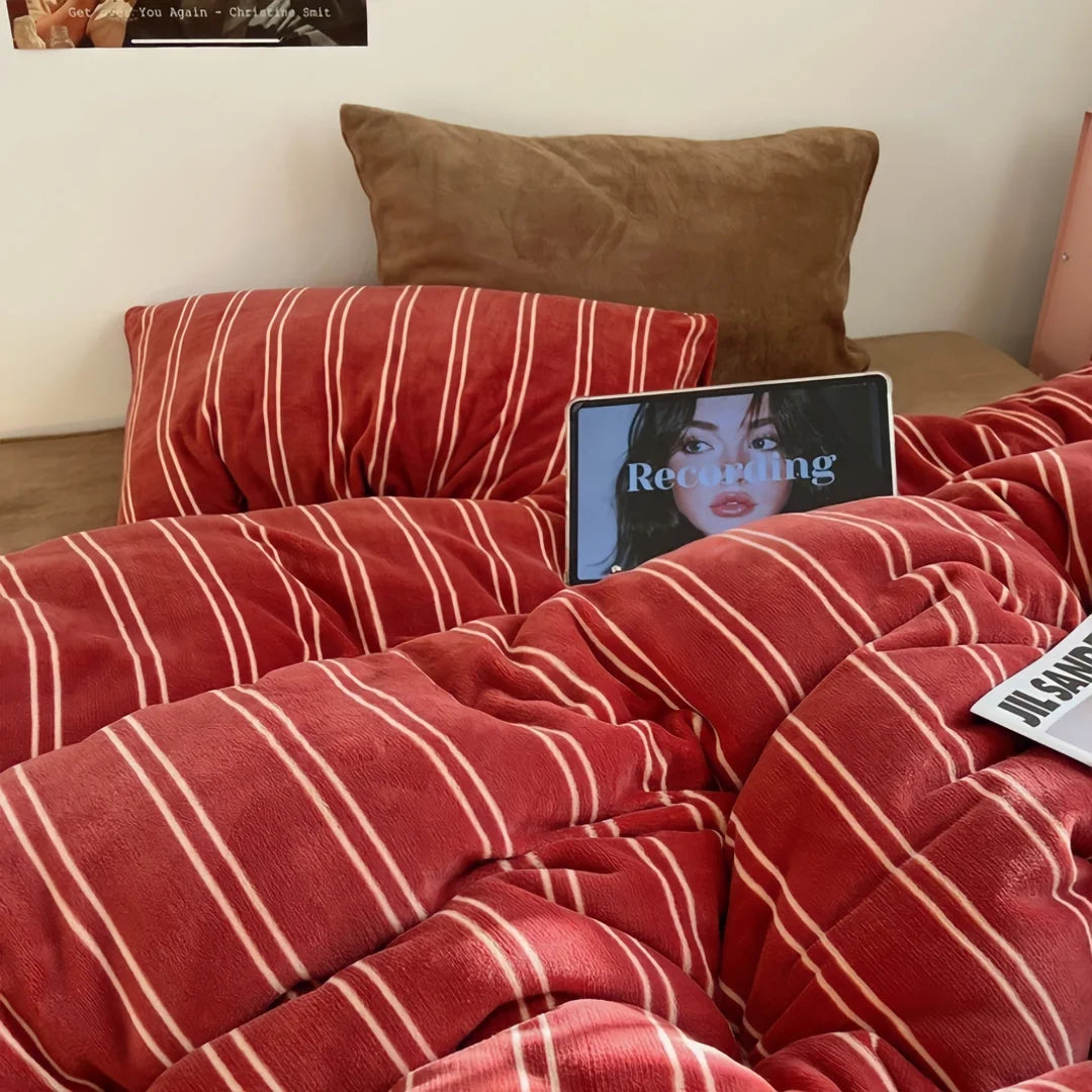A cozy bedroom scene featuring the red Plush Pinstripe Velvet Bedding Set, with a brown pillow and a tablet on the bed - RoomDen