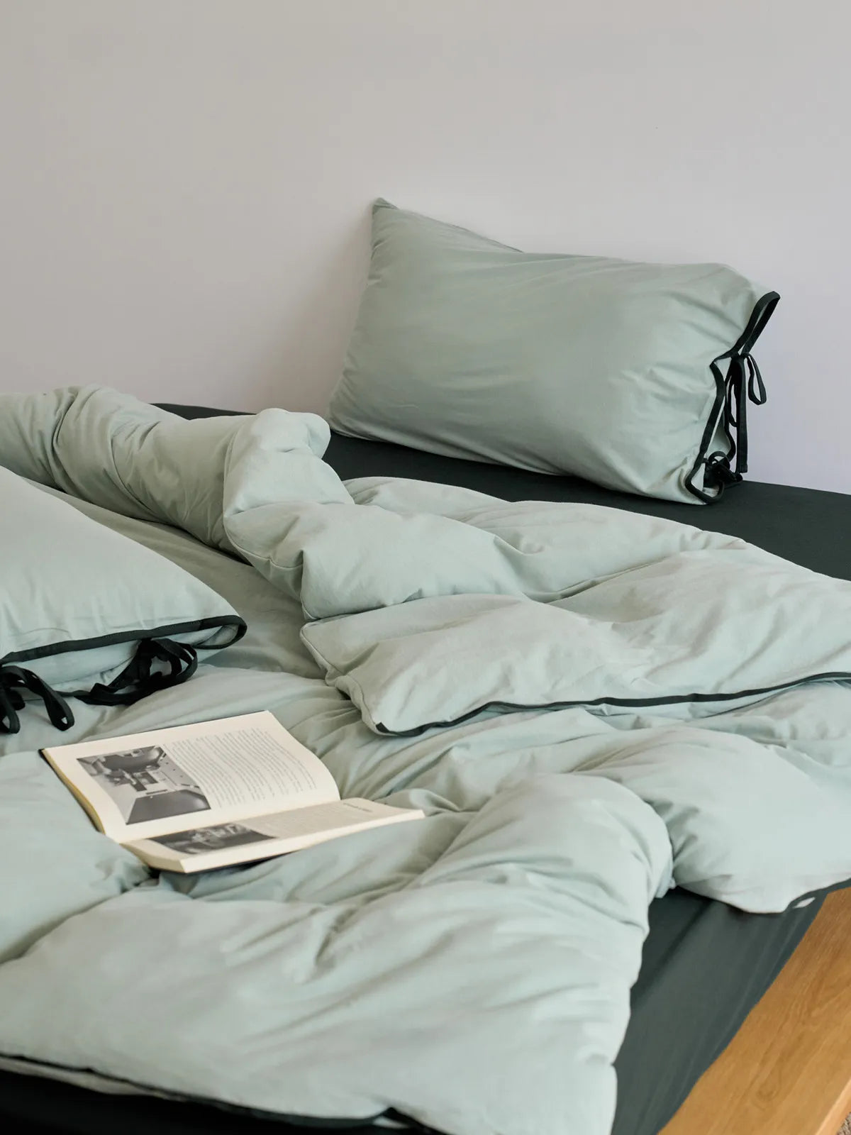 Close-up of the soft, wrinkled texture of the sage green washed cotton duvet cover. - RoomDen