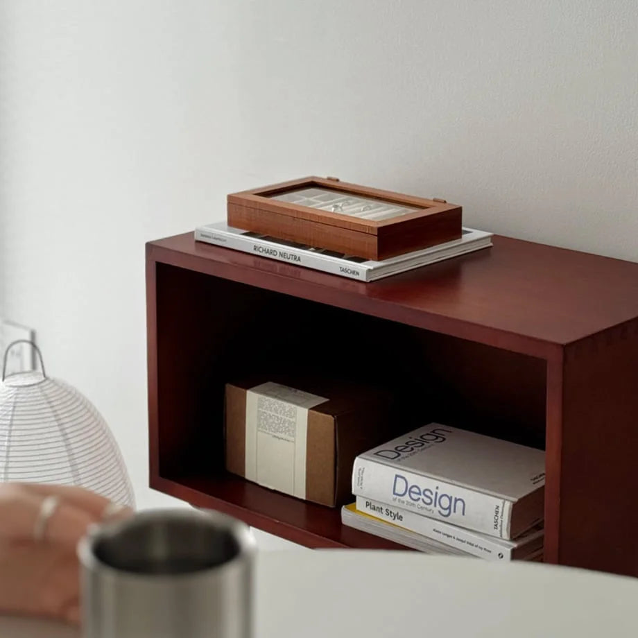 A close-up of the wood jewelry box on a modern side table, next to a white lamp.