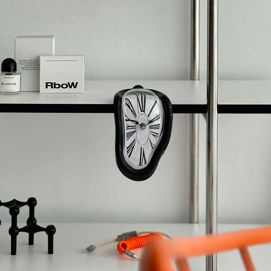 Close-up of the black Dali-inspired melting clock on a shelf edge. - RoomDen