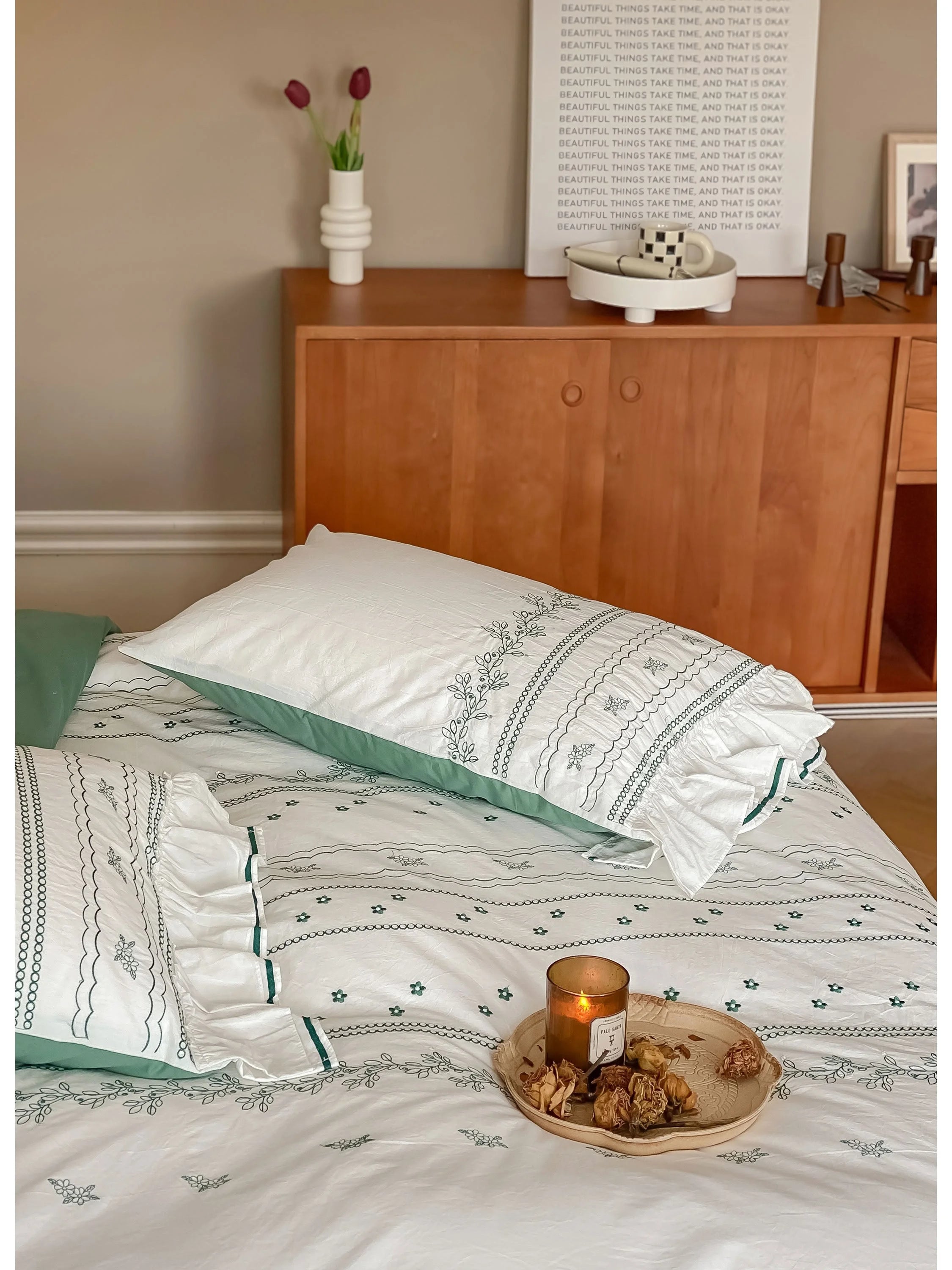 Detail shot of the pillow and duvet cover in Forest Green, with a candle and decor in the background.