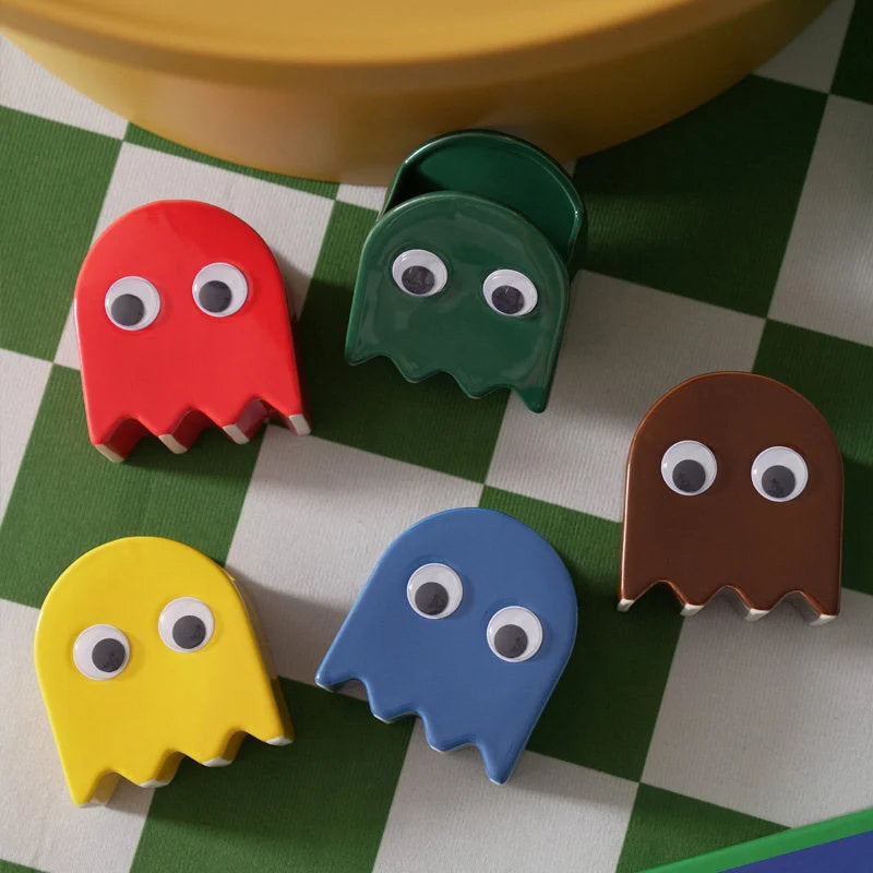 Top view of five colorful Retro Ghost Ceramic Pen Holders on a green and white checkered surface - RoomDen.