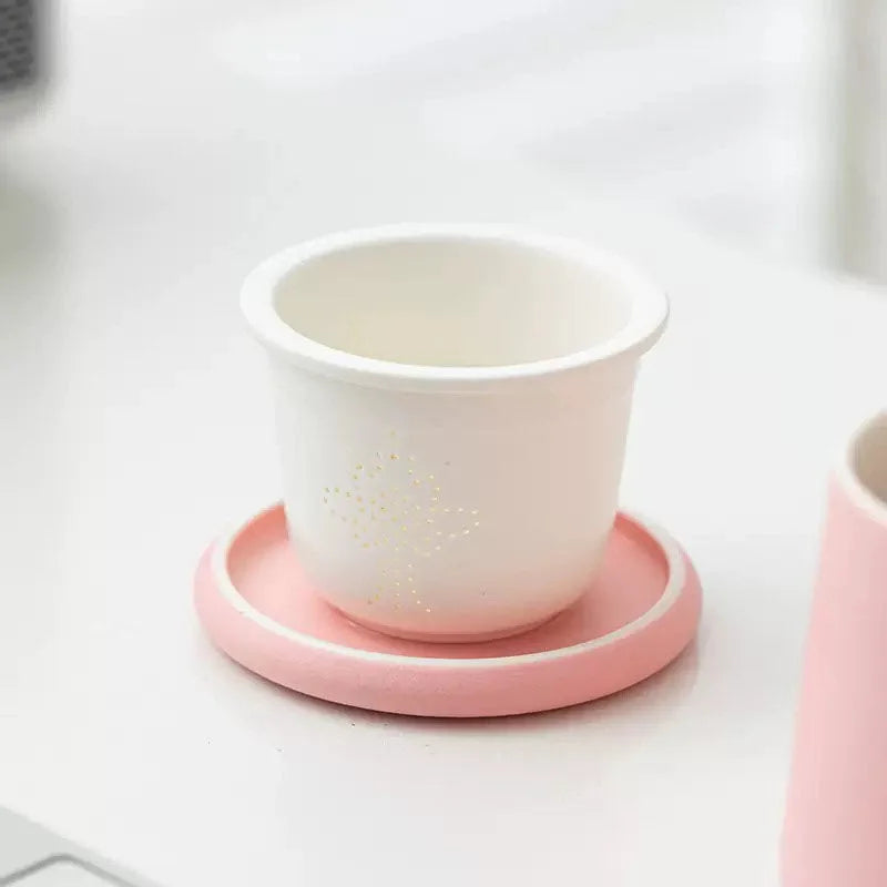 The inside of a pink ceramic mug showing a tea infuser, with the lid serving as a coaster - RoomDen.