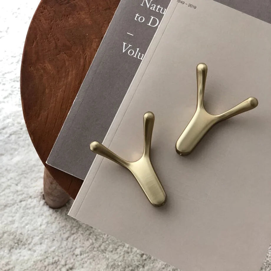 Overhead shot of two gold decorative hooks on books, sitting on a white textured rug - RoomDen