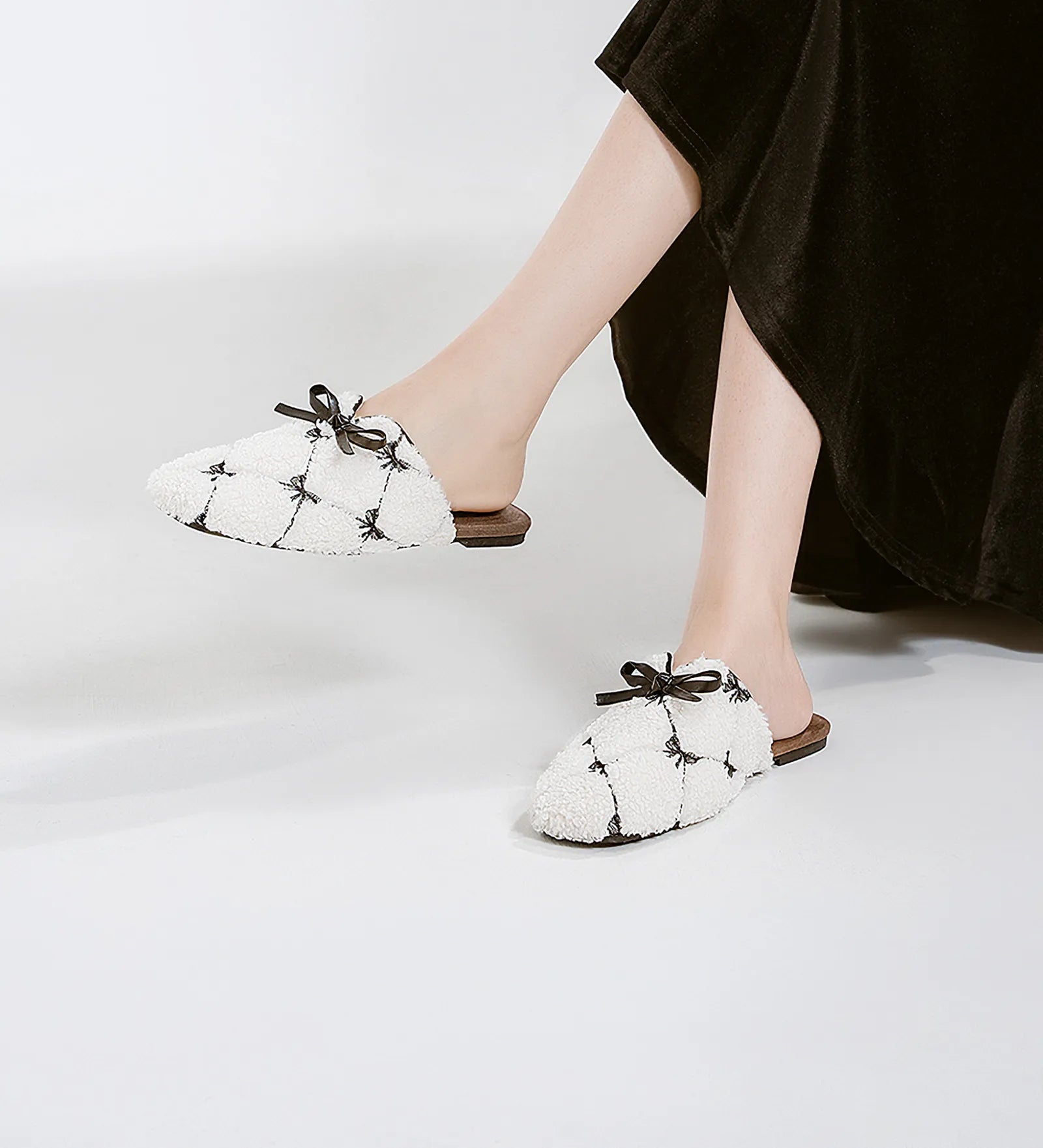 Side view of white quilted faux fur mules with brown flat sole