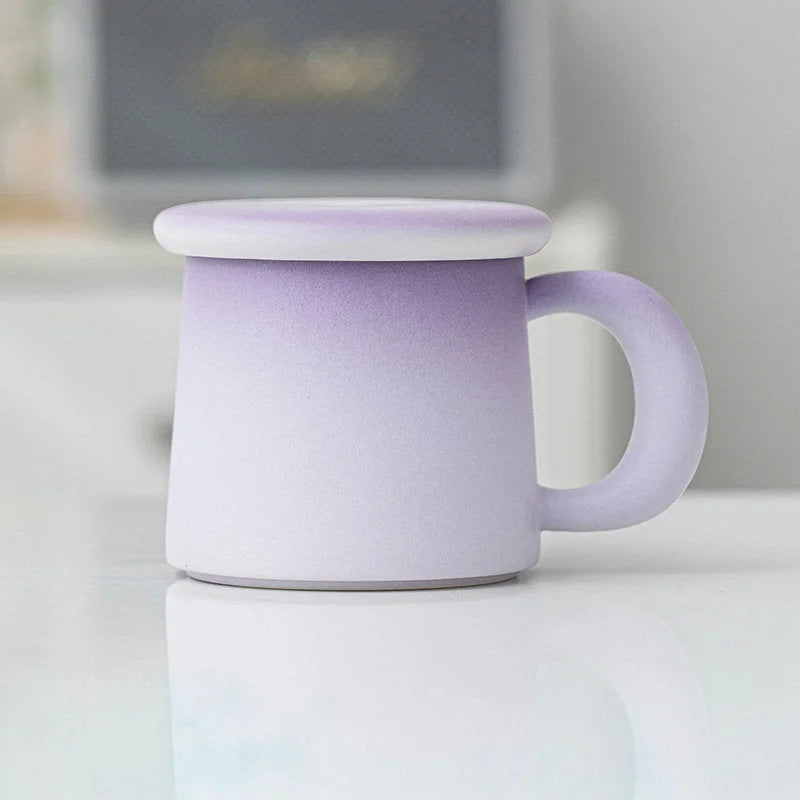 Side view of the Lavender Ombre Frosted Ceramic Mug with lid on a white reflective surface - RoomDen.