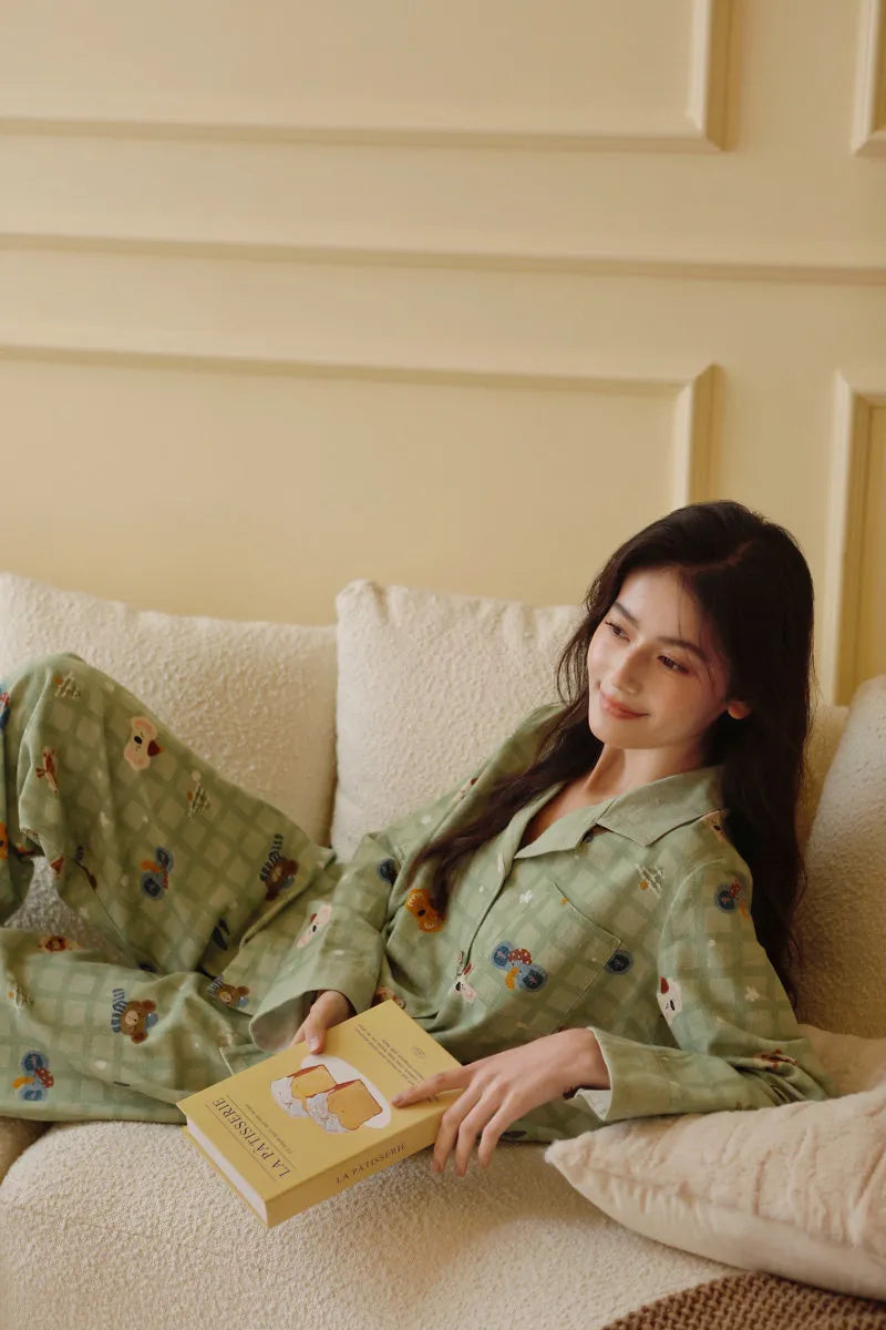 Lifestyle shot of woman lying on sofa reading a book in sage green plaid pajamas