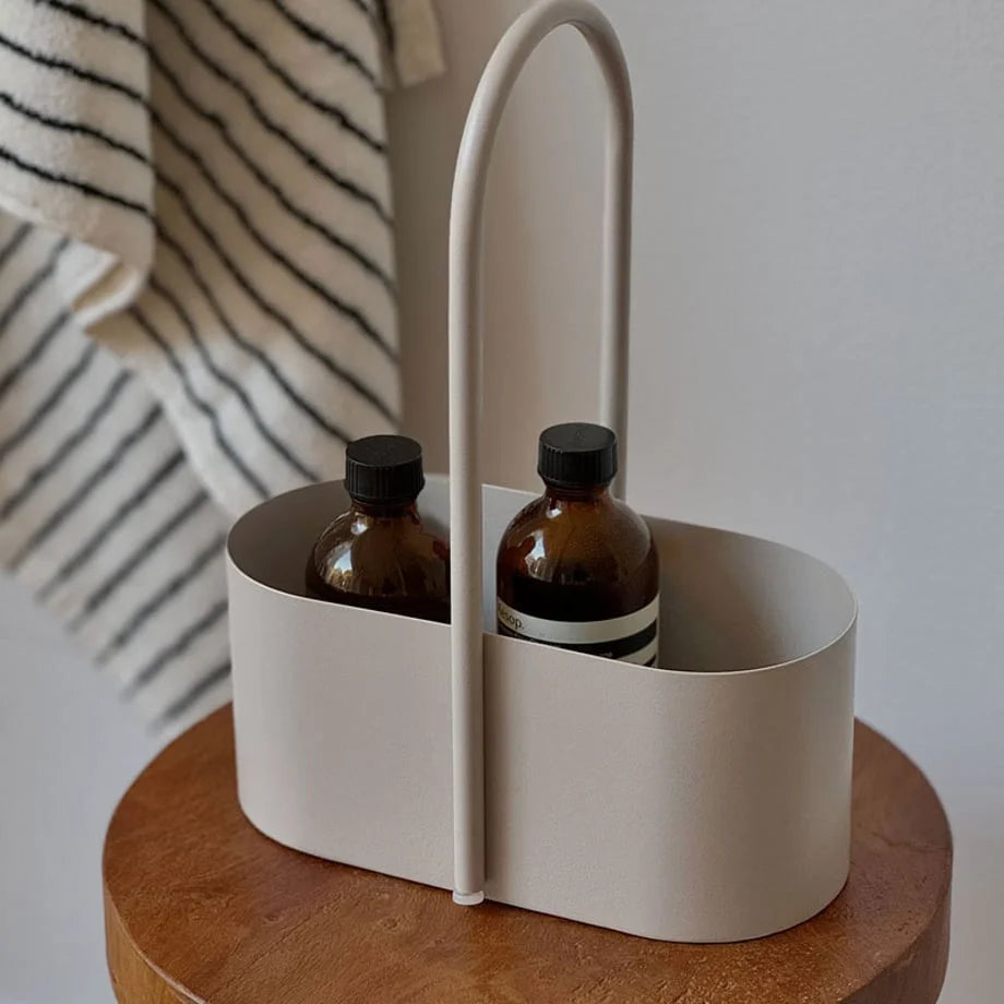 Close-up of the Japandi-style metal caddy showing its smooth handle and oval shape. - RoomDen