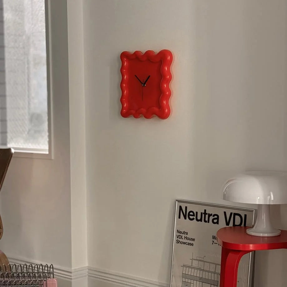 A vibrant red Wavy Squiggle Frame Clock on a white wall in a well-lit room with a mushroom lamp. - RoomDen