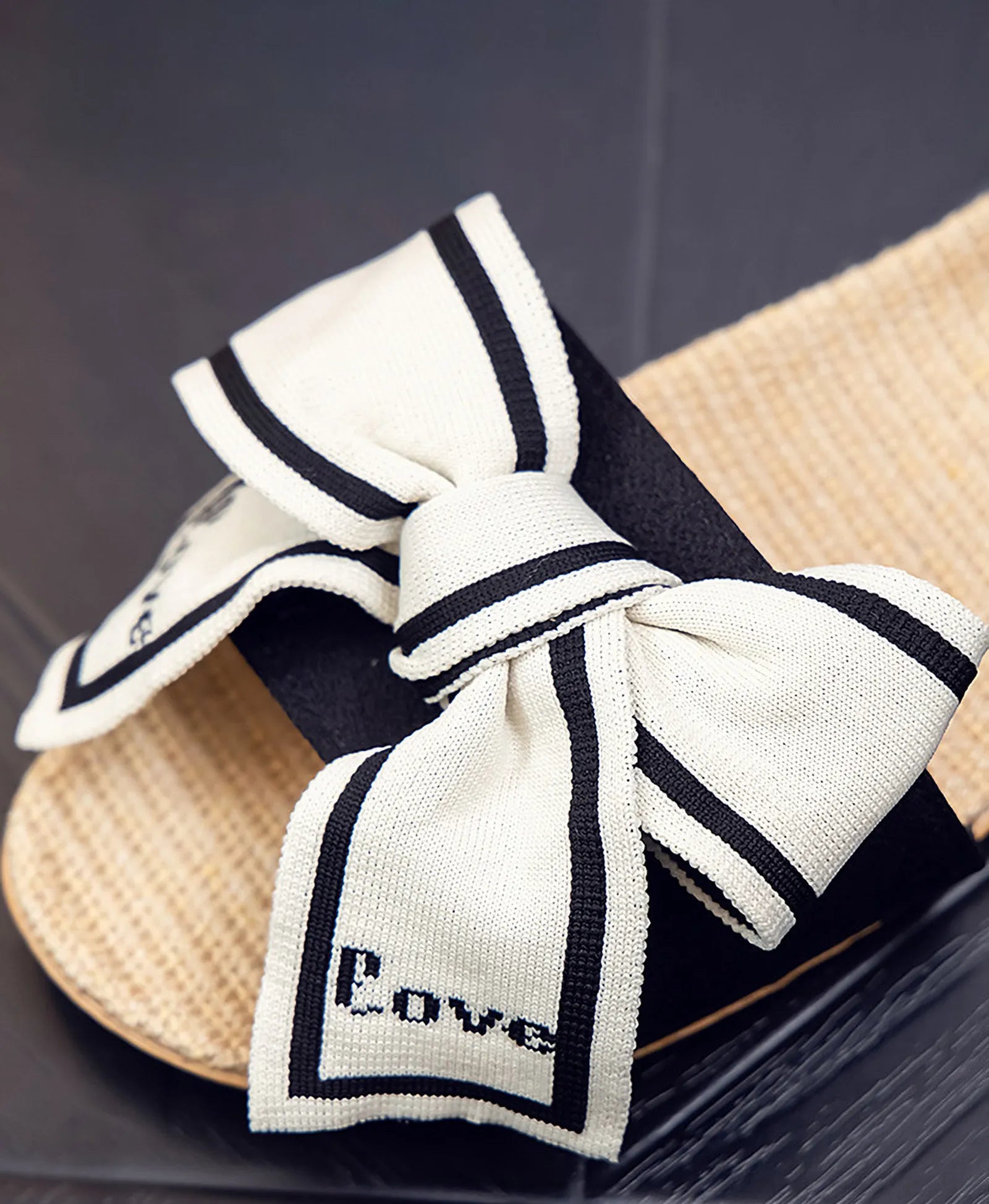 Close up detail of Black and Cream Bow with Love text on woven slippers