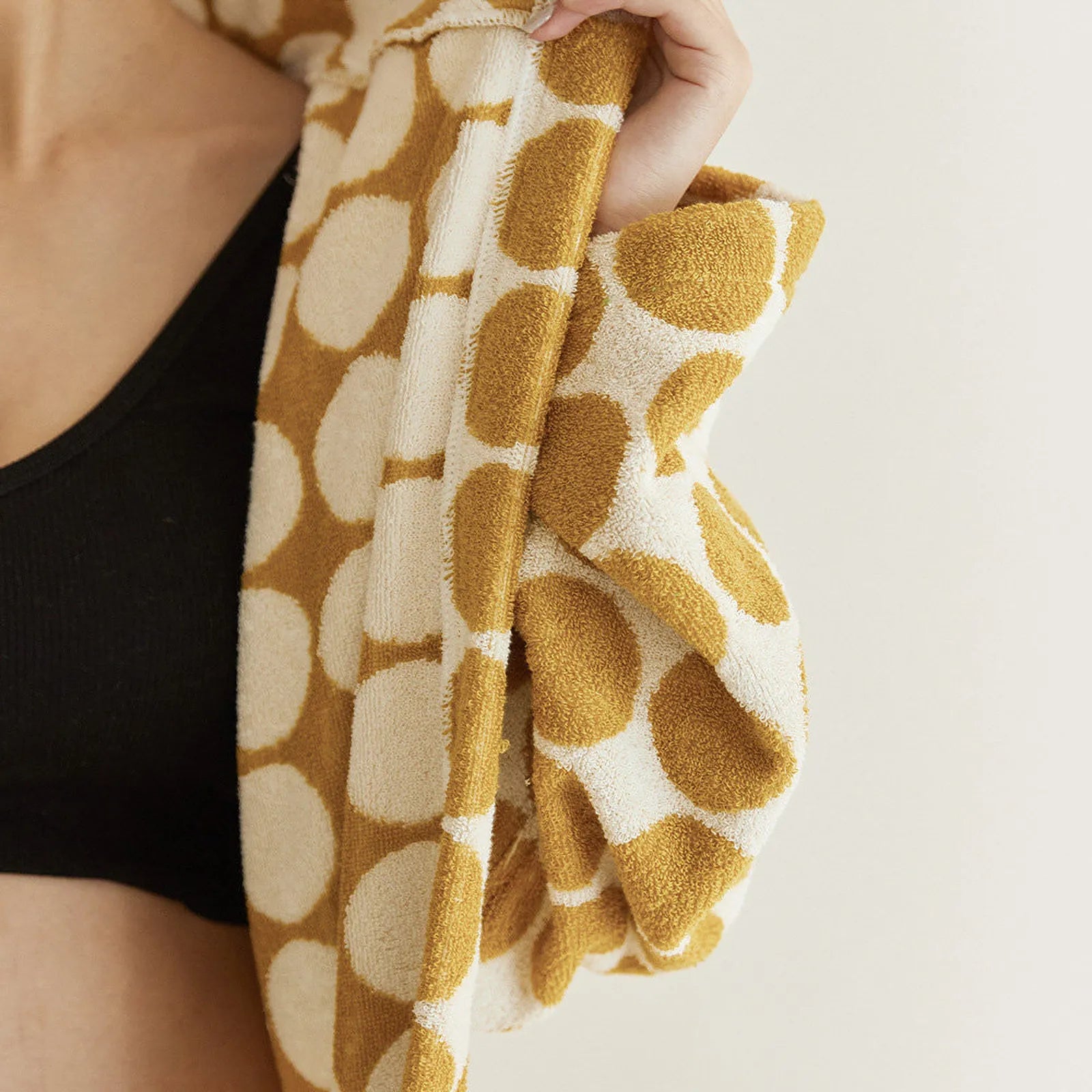 Folded yellow polka dot robe stacked neatly on a wooden chair - RoomDen