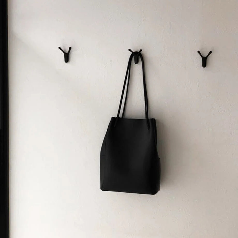 Variant Lifestyle: Three black branch-shaped metal wall hooks on a white wall, with a black tote bag hanging from the center hook - RoomDen