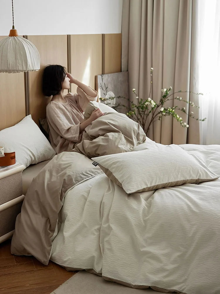 Lifestyle scene of a person relaxing in bed with the Cream White & Beige bedding in a sunlit room. - RoomDen