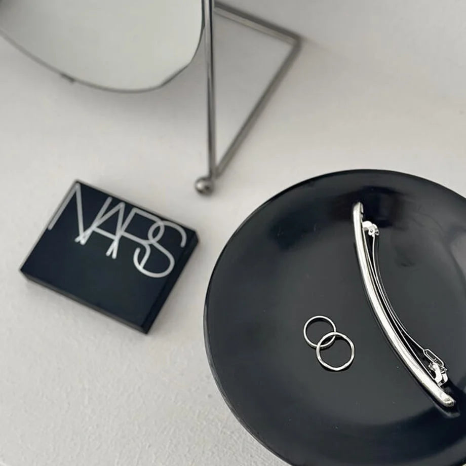 Macro shot of the silver rings inside the glossy black pedestal dish. - RoomDen