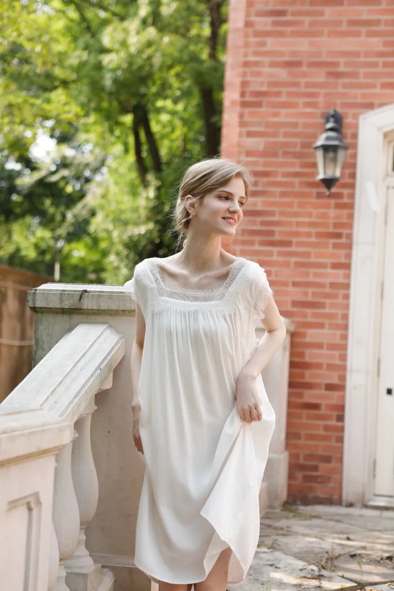 Model holding skirt of white cotton sateen dress in outdoor light - RoomDen