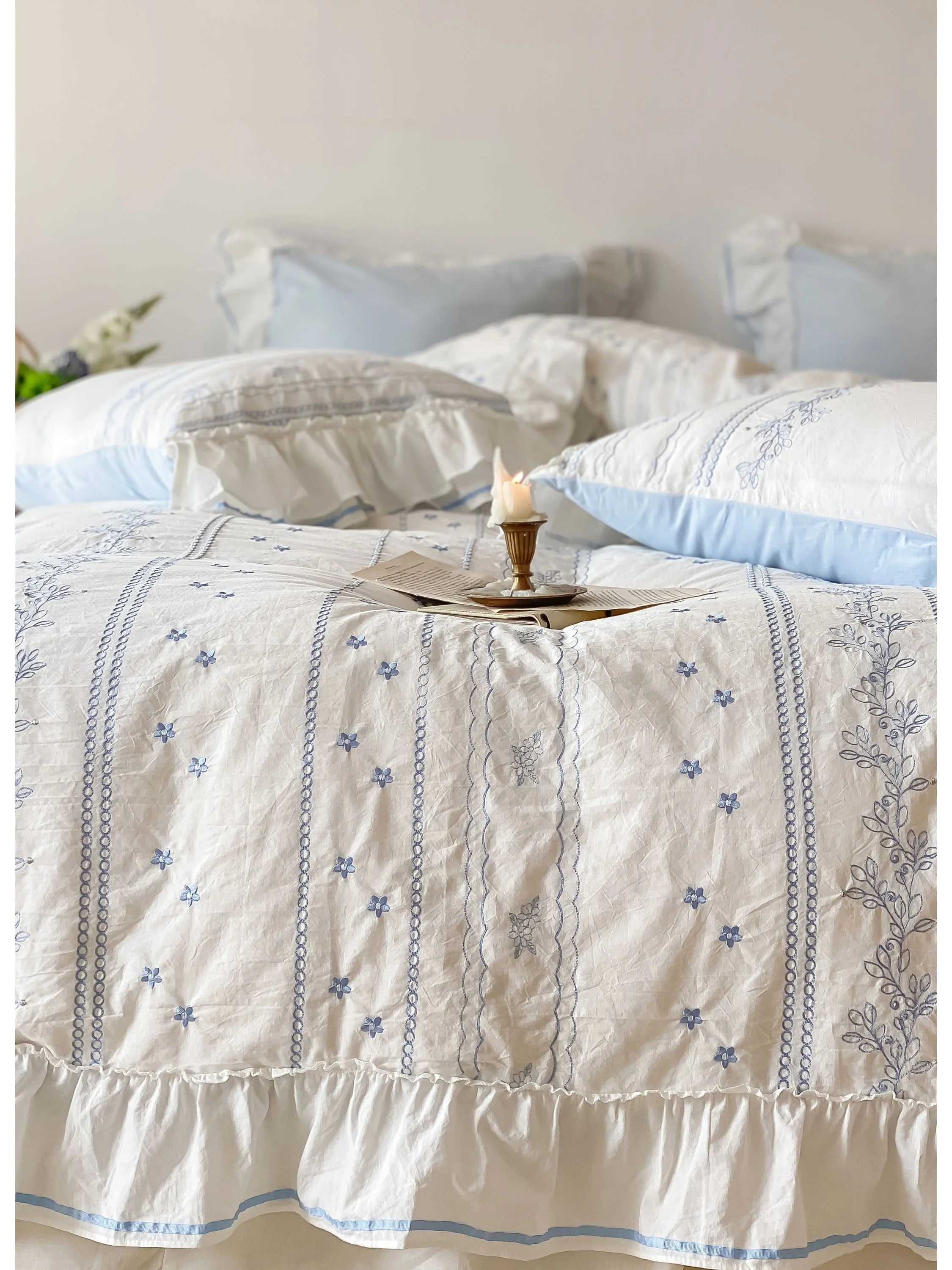 Detailed shot of the delicate floral vine embroidery and ruffled trim on the white and blue duvet cover.