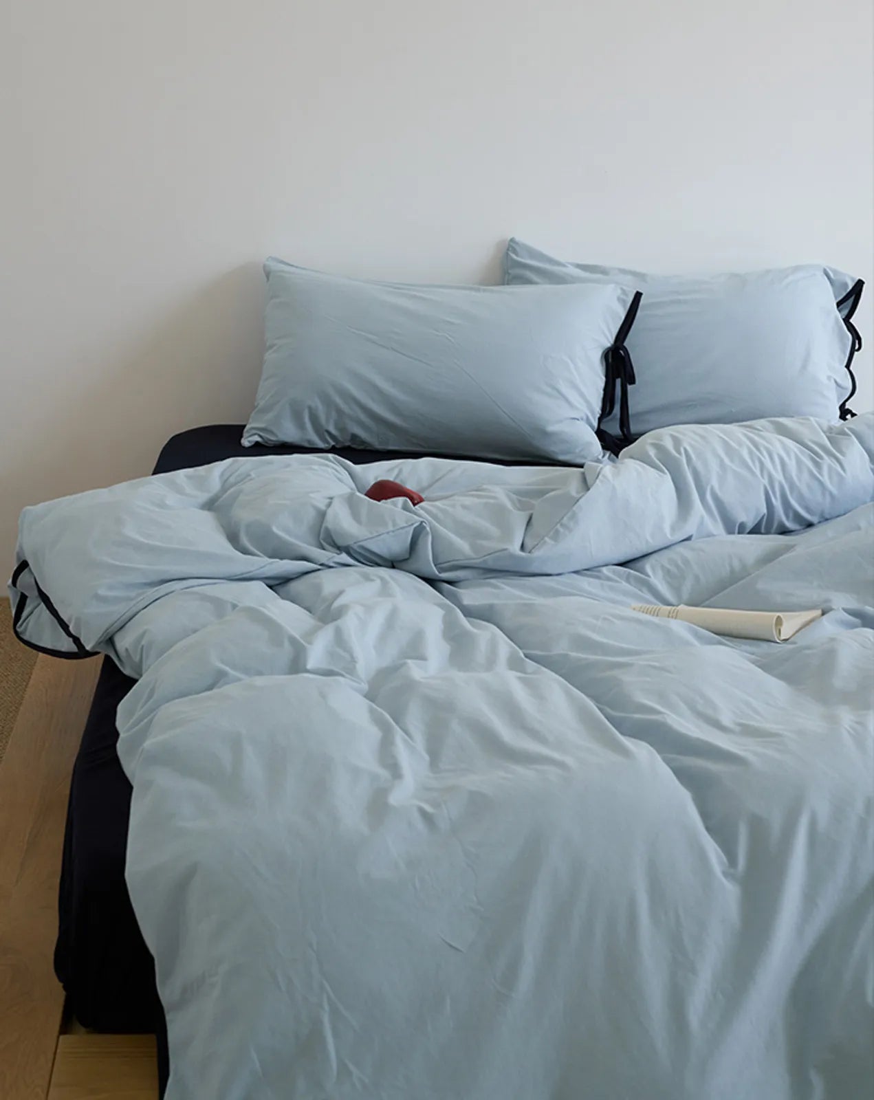 The light and airy Sky Blue & Black washed cotton bedding set styled on a bed. - RoomDen