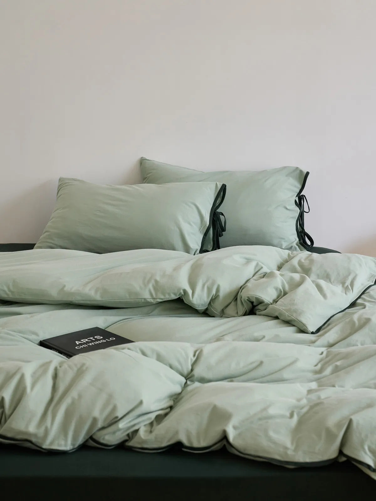 Front view of sage green coquette style bedding with ribbon ties.