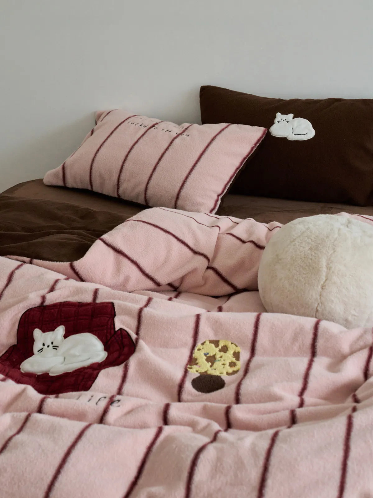 Styled pink cat embroidered bedding set with brown accent pillows RoomDen.